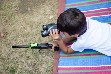 Delhi 'deki sosyete parkında oturup eğlenen sevimli küçük Hintli çocuk, etrafta çimen olan renkli minder üzerinde oturan sevimli bebek, açık havada ateş eden bebek.