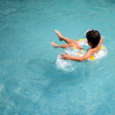 Havuzda yüzen mutlu Hintli çocuk, sıcak yaz tatillerinde hava tüpüyle birlikte yüzen çocuk, büyük bir havuzda yüzen çocuk..