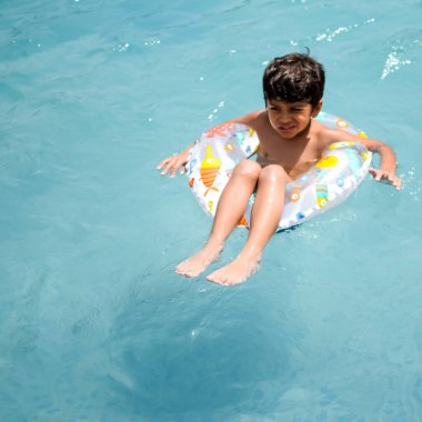 Havuzda yüzen mutlu Hintli çocuk, sıcak yaz tatillerinde hava tüpüyle birlikte yüzen çocuk, büyük bir havuzda yüzen çocuk..