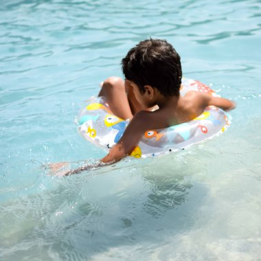 Havuzda yüzen mutlu Hintli çocuk, sıcak yaz tatillerinde hava tüpüyle birlikte yüzen çocuk, büyük bir havuzda yüzen çocuk..