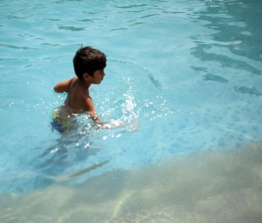 Havuzda yüzen mutlu Hintli çocuk, sıcak yaz tatillerinde hava tüpüyle birlikte yüzen çocuk, büyük bir havuzda yüzen çocuk..