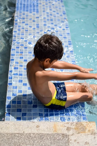 プールで泳ぐ幸せなインドの男の子 暑い夏休みの間に空気チューブと一緒に水泳衣装を着ている子供 大きなスイミングプールの子供たち ロイヤリティフリーのストック写真