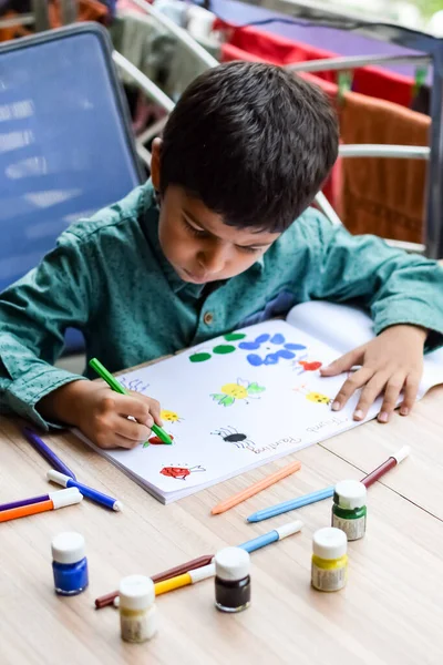 Inteligentny Indyjski Chłopiec Wykonać Malowanie Kciukiem Różnych Kolorach Wody Podczas — Zdjęcie stockowe