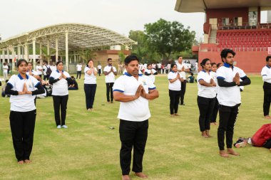 Yeni Delhi, Hindistan, 21 Haziran 2023 - Uluslararası Yoga Günü 'nde Delhi' deki Yamuna Spor Kompleksi 'nde grup Yoga egzersiz oturumu, kriket stadyumunda yoga derslerine katılan büyük bir grup yetişkin