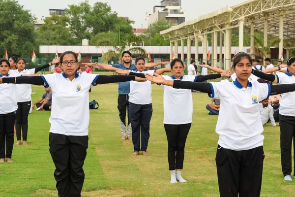 Yeni Delhi, Hindistan, 21 Haziran 2023 - Uluslararası Yoga Günü 'nde Delhi' deki Yamuna Spor Kompleksi 'nde grup Yoga egzersiz oturumu, kriket stadyumunda yoga derslerine katılan büyük bir grup yetişkin