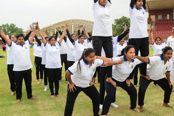 Yeni Delhi, Hindistan, 21 Haziran 2023 - Uluslararası Yoga Günü 'nde Delhi' deki Yamuna Spor Kompleksi 'nde grup Yoga egzersiz oturumu, kriket stadyumunda yoga derslerine katılan büyük bir grup yetişkin
