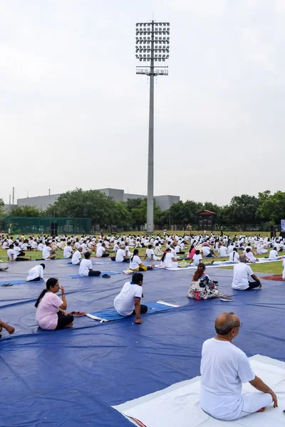 Yeni Delhi, Hindistan, 21 Haziran 2023 - Uluslararası Yoga Günü 'nde Delhi' deki Yamuna Spor Kompleksi 'nde grup Yoga egzersiz oturumu, kriket stadyumunda yoga derslerine katılan büyük bir grup yetişkin