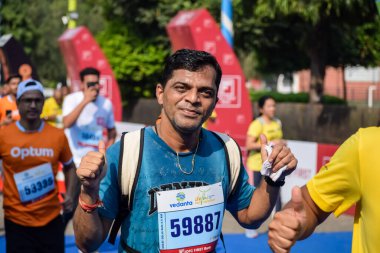 Yeni Delhi, Hindistan - 16 Ekim 2022 - Bitmek üzere olan maraton katılımcılarının bitiş çizgisini geçmek üzere olan Delhi Yarı Maratonu 2022