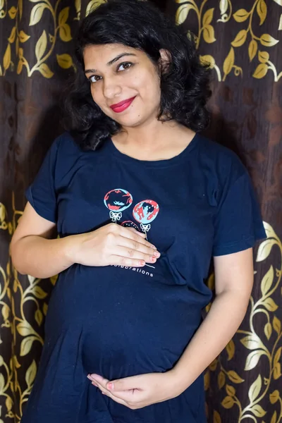 妊娠中のインド人女性がお腹に手を置き妊娠中のインド人女性は彼女の家の中で妊婦のドレスで彼女の胃に手を置きます — ストック写真