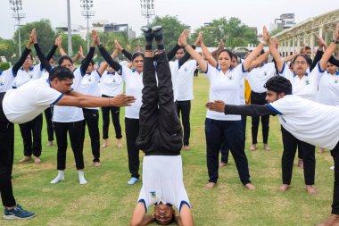 Yeni Delhi, Hindistan, 21 Haziran 2023 - Uluslararası Yoga Günü 'nde Delhi' deki Yamuna Spor Kompleksi 'nde grup Yoga egzersiz oturumu, kriket stadyumunda yoga derslerine katılan büyük bir grup yetişkin