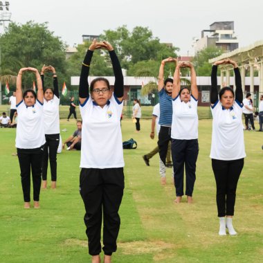 Yeni Delhi, Hindistan, 21 Haziran 2023 - Uluslararası Yoga Günü 'nde Delhi' deki Yamuna Spor Kompleksi 'nde grup Yoga egzersiz oturumu, kriket stadyumunda yoga derslerine katılan büyük bir grup yetişkin