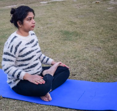 Young Indian woman practicing yoga outdoor in a park. Beautiful girl practice basic yoga pose. Calmness and relax, female happiness. Basic Yoga poses outdoor