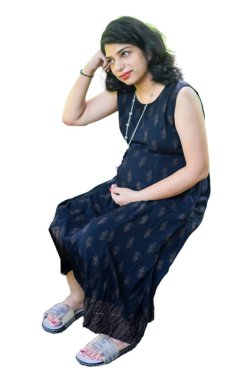 Hamile bir Hintli kadın hamilelik çekimi için poz veriyor ve elleri beyaz arka planda, Hintli hamile kadın elini karnının üstüne koyuyor.