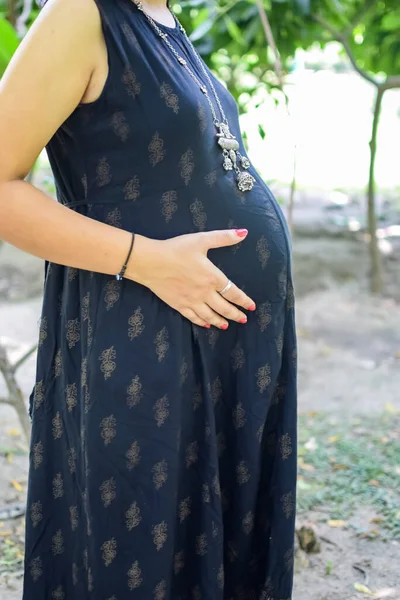 印度一位孕妇日前在社会公园里摆姿势 准备在户外拍摄怀孕照片 并把手放在肚子上 而印度孕妇则将自己的手放在肚子上 同时还将自己的一件孕妇装放在社会公园里 — 图库照片