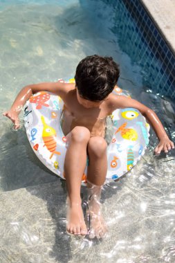 Havuzda yüzen mutlu Hintli çocuk, sıcak yaz tatillerinde hava tüpüyle birlikte yüzen çocuk, büyük bir havuzda yüzen çocuk..