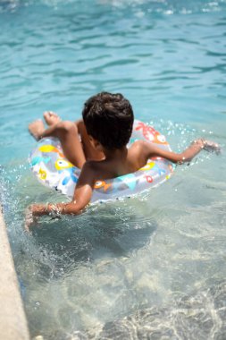 Havuzda yüzen mutlu Hintli çocuk, sıcak yaz tatillerinde hava tüpüyle birlikte yüzen çocuk, büyük bir havuzda yüzen çocuk..