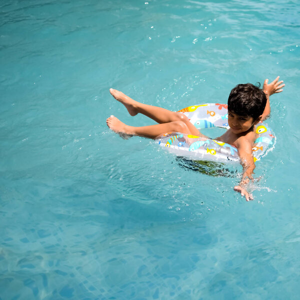 Счастливый индийский мальчик плавает в бассейне, Ребенок в купальном костюме вместе с воздуходувкой во время жарких летних каникул, Детский мальчик в большом бассейне.