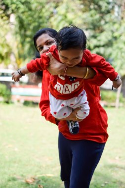 Sosyete parkında bebeğini taşıyan bir anne. Mutlu bir annenin parlak portresi. Çocuğu elinde tutuyor. Anne, 9 aylık oğluna sarılıyor..