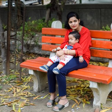 Sosyete parkında bebeğini taşıyan bir anne. Mutlu bir annenin parlak portresi. Çocuğu elinde tutuyor. Anne, 9 aylık oğluna sarılıyor..