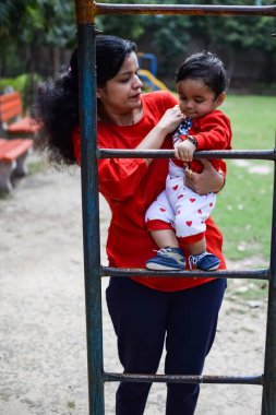 Sosyete parkında bebeğini taşıyan bir anne. Mutlu bir annenin parlak portresi. Çocuğu elinde tutuyor. Anne, 9 aylık oğluna sarılıyor..