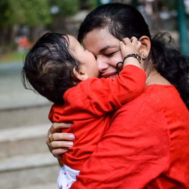 Sosyete parkında bebeğini taşıyan bir anne. Mutlu bir annenin parlak portresi. Çocuğu elinde tutuyor. Anne, 9 aylık oğluna sarılıyor..