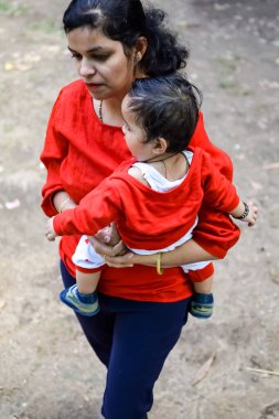 Sosyete parkında bebeğini taşıyan bir anne. Mutlu bir annenin parlak portresi. Çocuğu elinde tutuyor. Anne, 9 aylık oğluna sarılıyor..