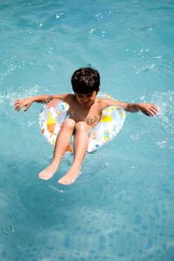 Havuzda yüzen mutlu Hintli çocuk, sıcak yaz tatillerinde hava tüpüyle birlikte yüzen çocuk, büyük bir havuzda yüzen çocuk..