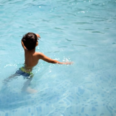 Havuzda yüzen mutlu Hintli çocuk, sıcak yaz tatillerinde hava tüpüyle birlikte yüzen çocuk, büyük bir havuzda yüzen çocuk..