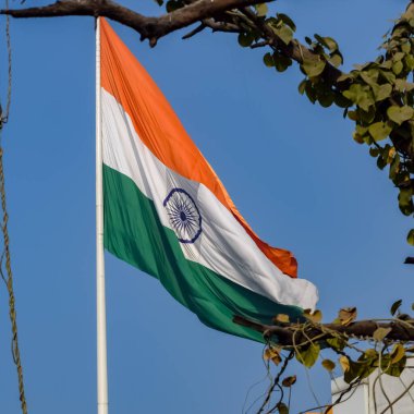 India flag flying high at Connaught Place with pride in blue sky, India flag fluttering, Indian Flag on Independence Day and Republic Day of India, tilt up shot, Waving Indian flag, Har Ghar Tiranga