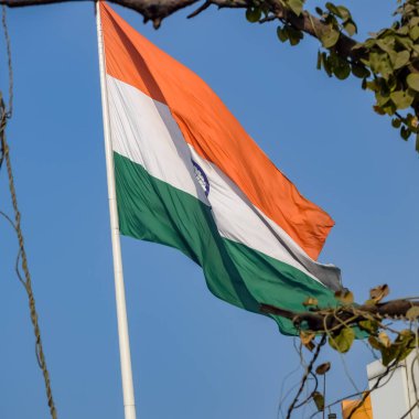 India flag flying high at Connaught Place with pride in blue sky, India flag fluttering, Indian Flag on Independence Day and Republic Day of India, tilt up shot, Waving Indian flag, Har Ghar Tiranga
