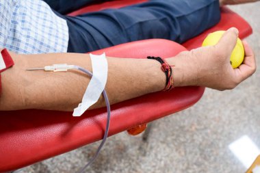Blood donor at Blood donation camp held with a bouncy ball holding in hand at Balaji Temple, Vivek Vihar, Delhi, India, Image for World blood donor day on June 14 every year, Blood Donation Camp