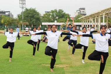 Yeni Delhi, Hindistan, 21 Haziran 2023 - Uluslararası Yoga Günü 'nde Delhi' deki Yamuna Spor Kompleksi 'nde grup Yoga egzersiz oturumu, kriket stadyumunda yoga derslerine katılan büyük bir grup yetişkin