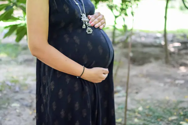 妊娠中のインドの女性は 腹に屋外妊娠の撮影と手をポーズ インドの妊娠中の女性は 社会公園で母性のドレスで彼女の手を置きます 妊娠中の外出産の撮影 — ストック写真