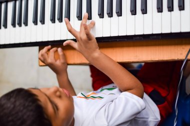 Sentezleyici ya da piyano çalan Asyalı çocuk. Küçük şirin çocuk piyano çalmayı öğreniyor. Çocuk elleri klavyenin içinde.