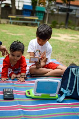 Sosyete parkında iki mutlu çocuk, birlikte mutlu gülümseyen mutlu Asyalı kardeşler. Kardeşler yazın dışarıda oynar, en iyi arkadaşlar. Küçük oğlan mutlu erkek kardeşiyle bahçede oynuyor.