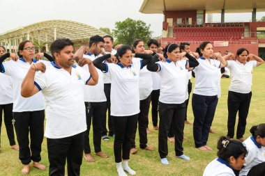 Yeni Delhi, Hindistan, 21 Haziran 2023 - Uluslararası Yoga Günü 'nde Delhi' deki Yamuna Spor Kompleksi 'nde grup Yoga egzersiz oturumu, kriket stadyumunda yoga derslerine katılan büyük bir grup yetişkin