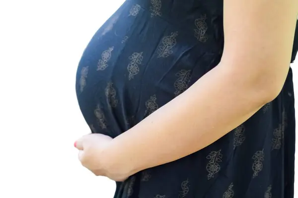 一位印度孕妇在怀孕时摆姿势 双手放在有白色背景的肚子上 而一位印度孕妇则穿着朴素背景的孕妇装 双手放在肚子上 孕妇照 — 图库照片