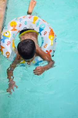 Havuzda yüzen mutlu Hintli çocuk, sıcak yaz tatillerinde hava tüpüyle birlikte yüzen çocuk, büyük bir havuzda yüzen çocuk..