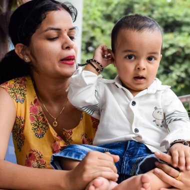Sevgi dolu anne bebeğini balkonda taşıyor. Mutlu bir annenin parlak portresi. Çocuğu elinde tutuyor. Anne ve 1 yaşındaki küçük oğlu..