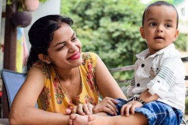 Sevgi dolu anne bebeğini balkonda taşıyor. Mutlu bir annenin parlak portresi. Çocuğu elinde tutuyor. Anne ve 1 yaşındaki küçük oğlu..