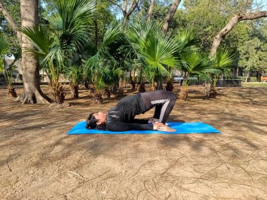 Young Indian woman practicing yoga outdoor in a park. Beautiful girl practice basic yoga pose. Calmness and relax, female happiness. Basic Yoga poses outdoor