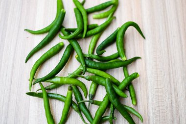 Sade ahşap masada taze yeşil biber, tüm temel gıdalar için yeşil sebzeler, sade arka planda soyulmamış sebzelerin manzarası