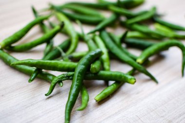 Sade ahşap masada taze yeşil biber, tüm temel gıdalar için yeşil sebzeler, sade arka planda soyulmamış sebzelerin manzarası