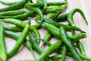 Sade ahşap masada taze yeşil biber, tüm temel gıdalar için yeşil sebzeler, sade arka planda soyulmamış sebzelerin manzarası