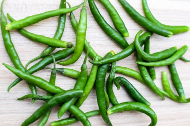 Sade ahşap masada taze yeşil biber, tüm temel gıdalar için yeşil sebzeler, sade arka planda soyulmamış sebzelerin manzarası