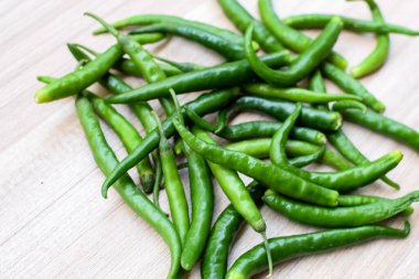 Sade ahşap masada taze yeşil biber, tüm temel gıdalar için yeşil sebzeler, sade arka planda soyulmamış sebzelerin manzarası