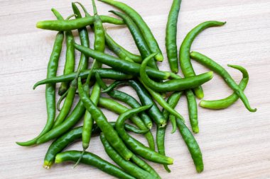 Sade ahşap masada taze yeşil biber, tüm temel gıdalar için yeşil sebzeler, sade arka planda soyulmamış sebzelerin manzarası