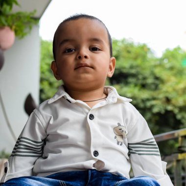 Erkek bebek balkonda. Masada oturan mutlu çocuğun parlak portresi. Evin balkonunda gündüz vakti 1 yaşında küçük bir çocuk..