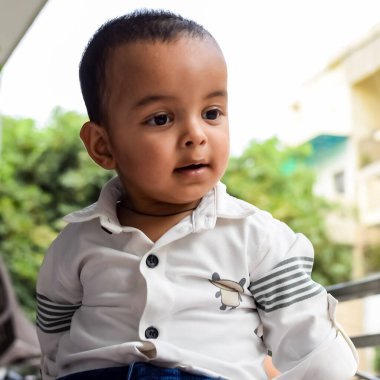 Erkek bebek balkonda. Masada oturan mutlu çocuğun parlak portresi. Evin balkonunda gündüz vakti 1 yaşında küçük bir çocuk..