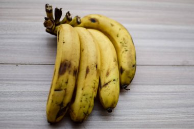 Sade ahşap masada taze meyve muzu, tüm temel yiyecekler için temel meyveler, sade arka planda soyulmamış taze muz manzarası.